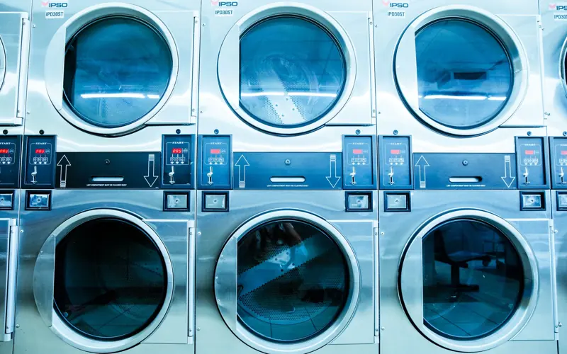 A row of modern washing machines in a launderette, showcasing contemporary laundry technology.