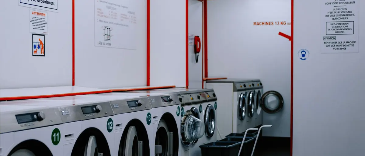 Inside a laundromat with washing machines lined up against the wall.