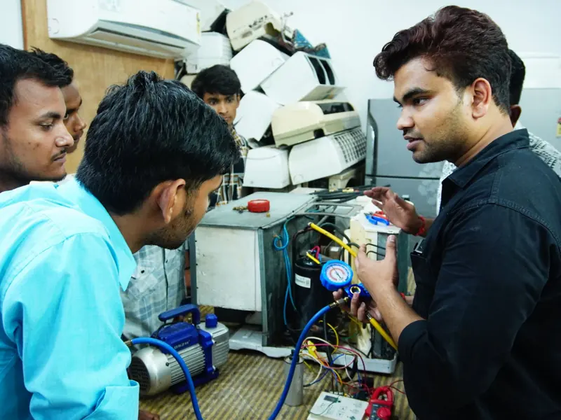 Participants learn AC repair during a hands-on session in Delhi, India.