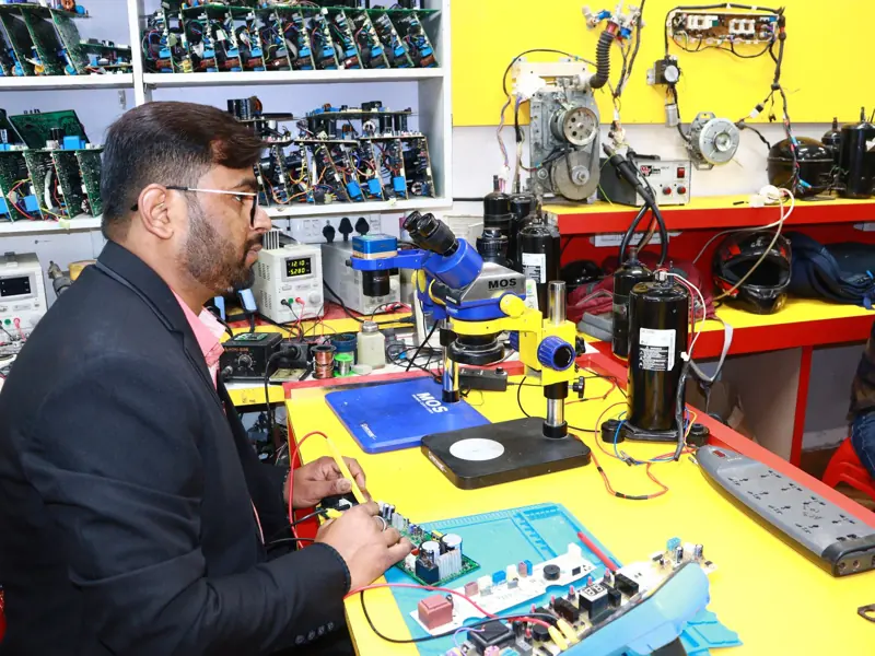 A man in Delhi working in an electronics lab with tools and components.