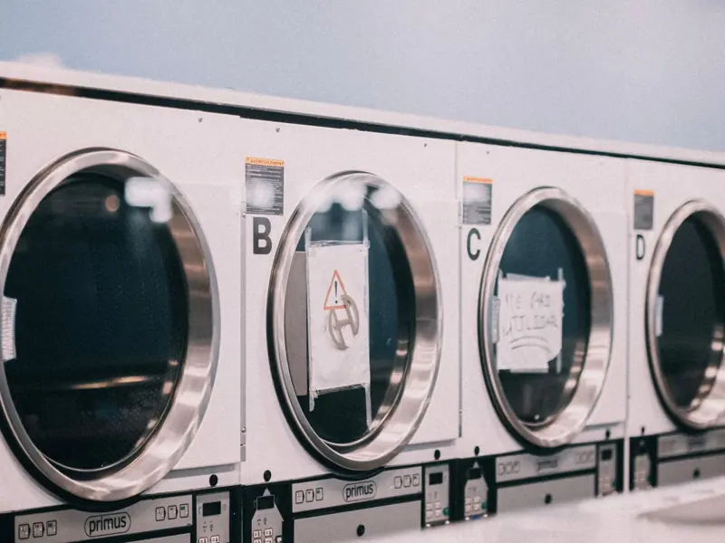 A series of industrial washing machines labeled A to D in a modern laundromat setting.