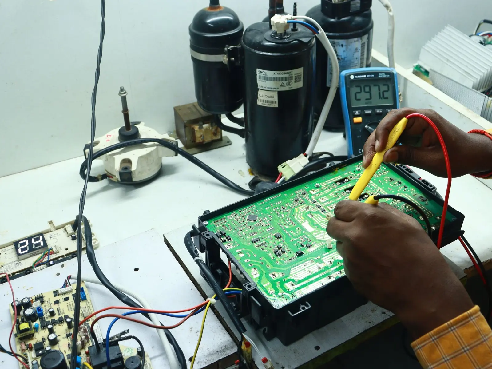 Technician working on AC PCB with tools and equipment, captured in New Delhi workshop.