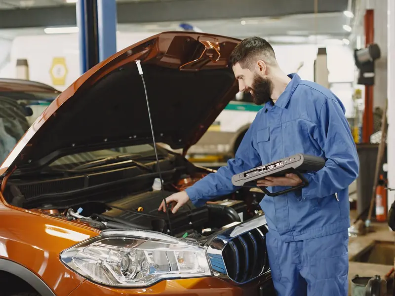 Skilled mechanic working on car engine diagnostics in a modern garage.