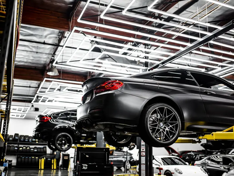A modern car repair shop showcasing vehicles on lifts and a well-lit, organized interior.