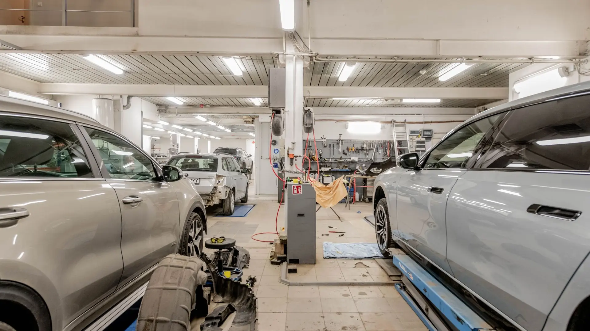 Interior of an automotive repair shop with cars undergoing maintenance and servicing.