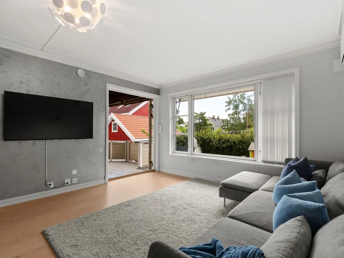 Spacious living room with modern decor, large window view, and wall-mounted TV.