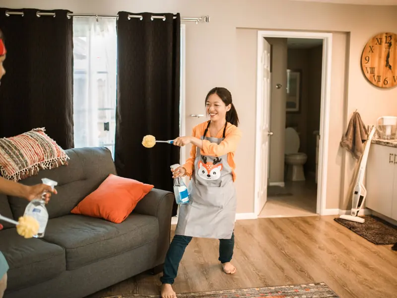 A cheerful couple engages in a playful cleaning session in their home.