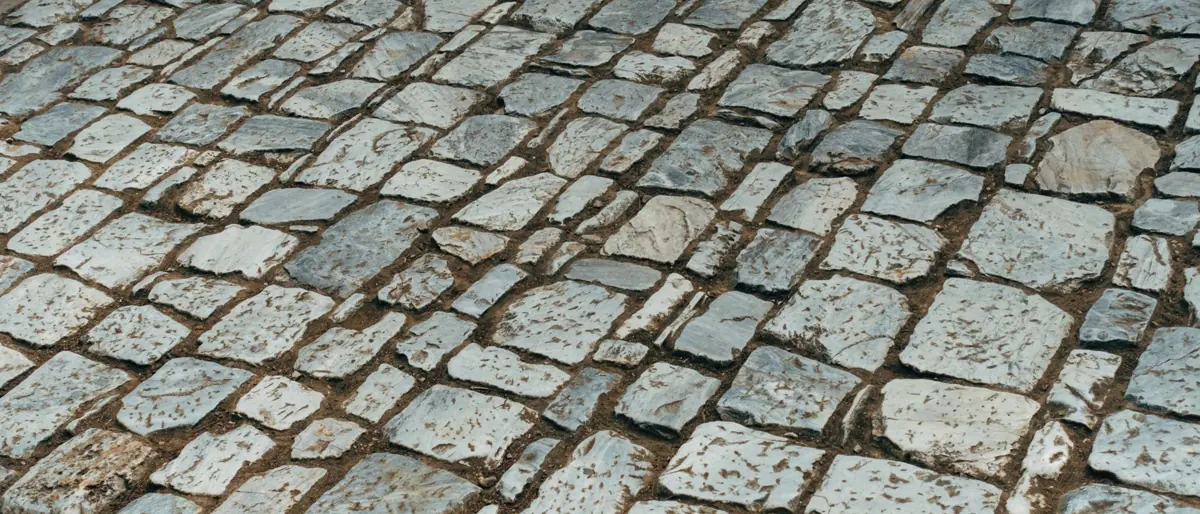 Old cobblestone path featuring granite stones in a classic pattern, offering a textured surface view.