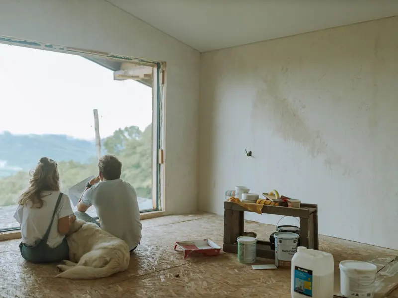 A couple with their dog resting in a partially renovated room, planning the renovation.