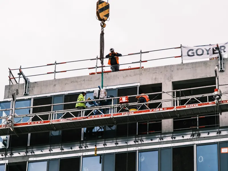 Professional workers at a construction site managing equipment on a high-rise building.