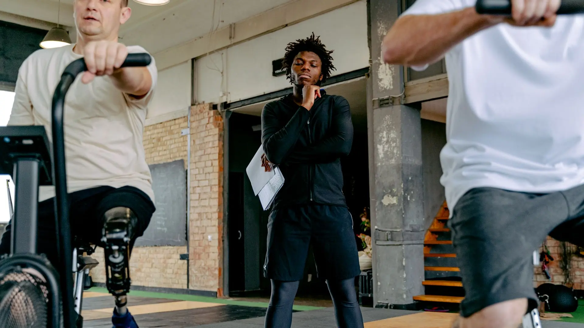 An inclusive fitness session featuring adults with prosthetic legs cycling under guidance.