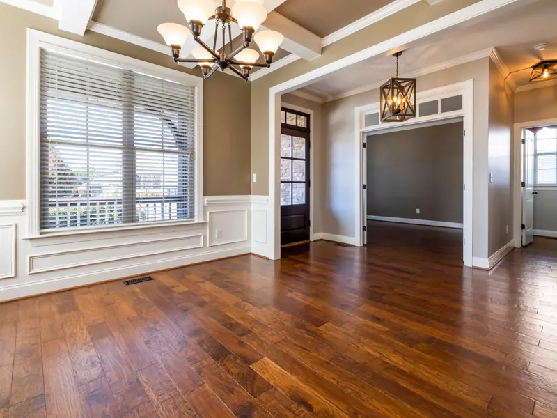 Elegant room with wooden flooring, chandelier, and natural lighting.