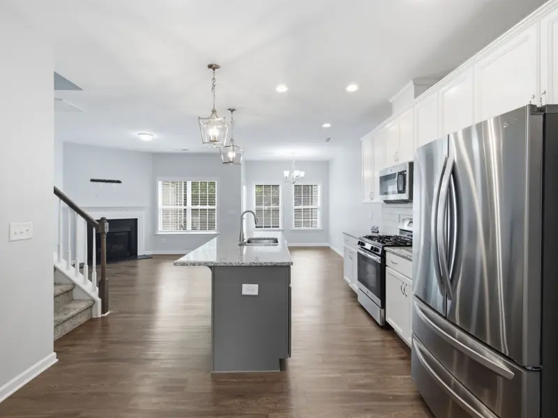 Bright and airy kitchen showcasing stainless steel appliances, hardwood floors, and contemporary lighting.