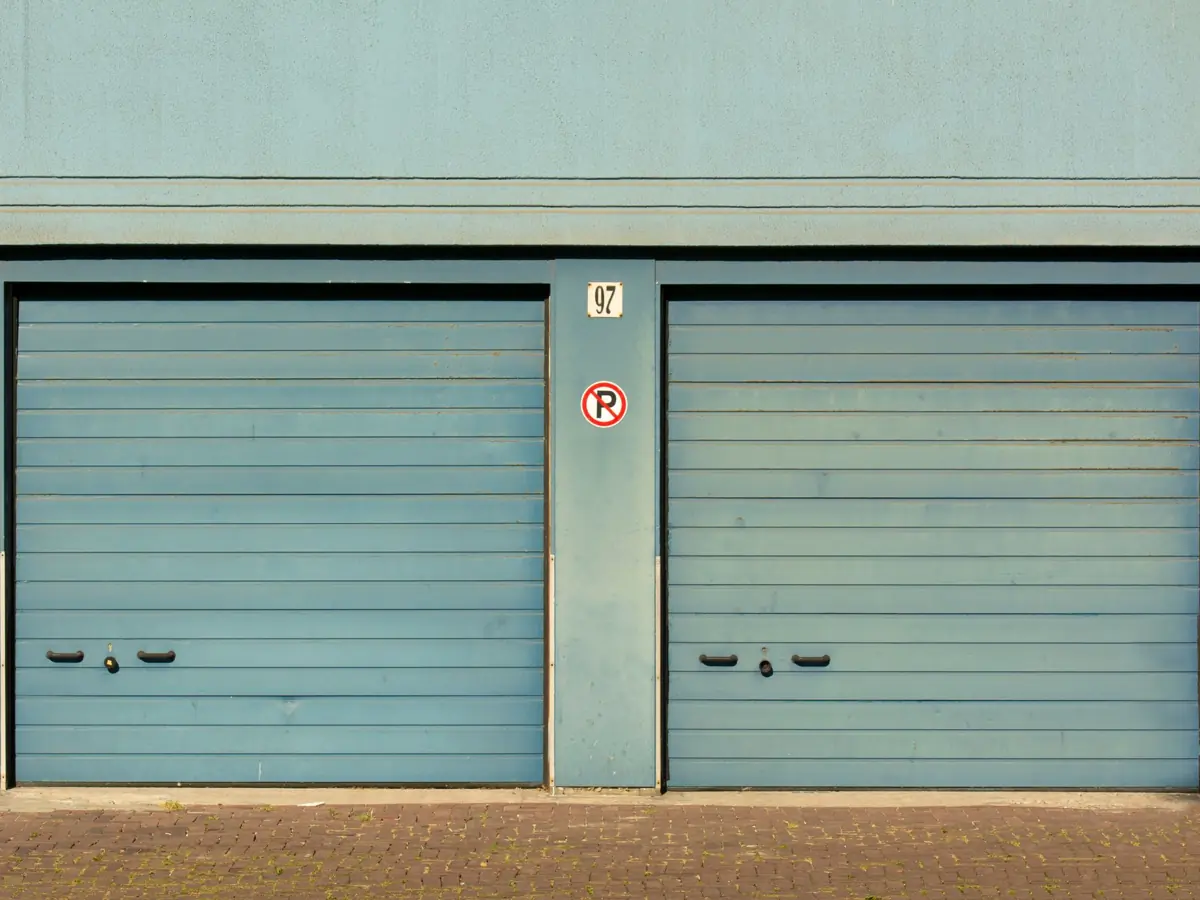 Blue garage doors with a no parking sign painted outdoors.
