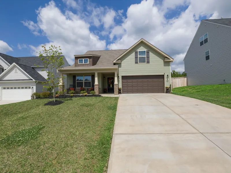 A modern suburban detached house with a spacious driveway under a bright blue sky.