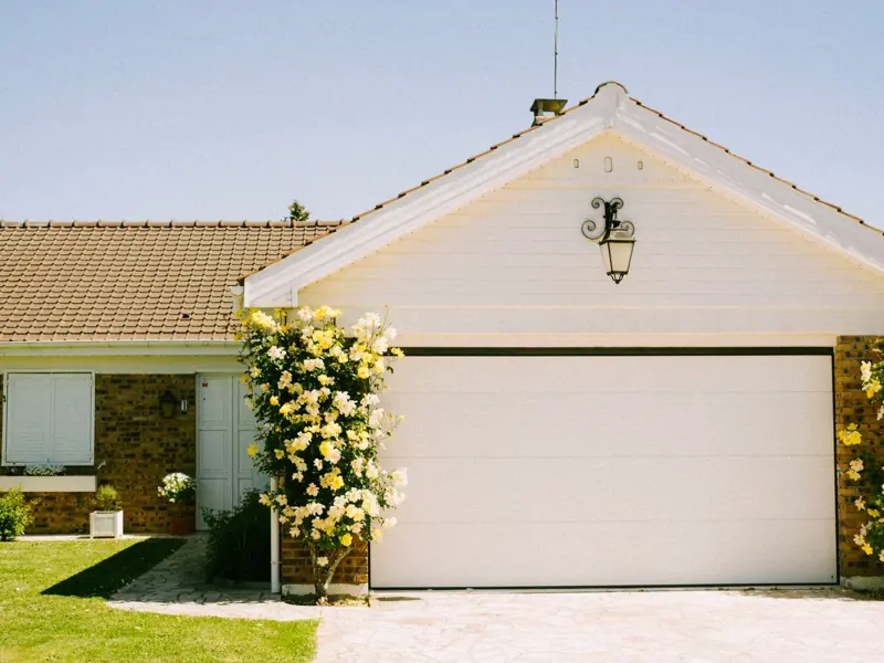 A lovely suburban home with a prominent garage and flowering plants, epitomizing suburban charm and tranquility.