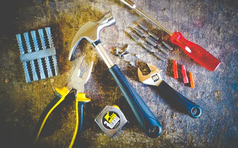 Collection of hand tools including hammer, screwdriver, and pliers in a workshop setting.