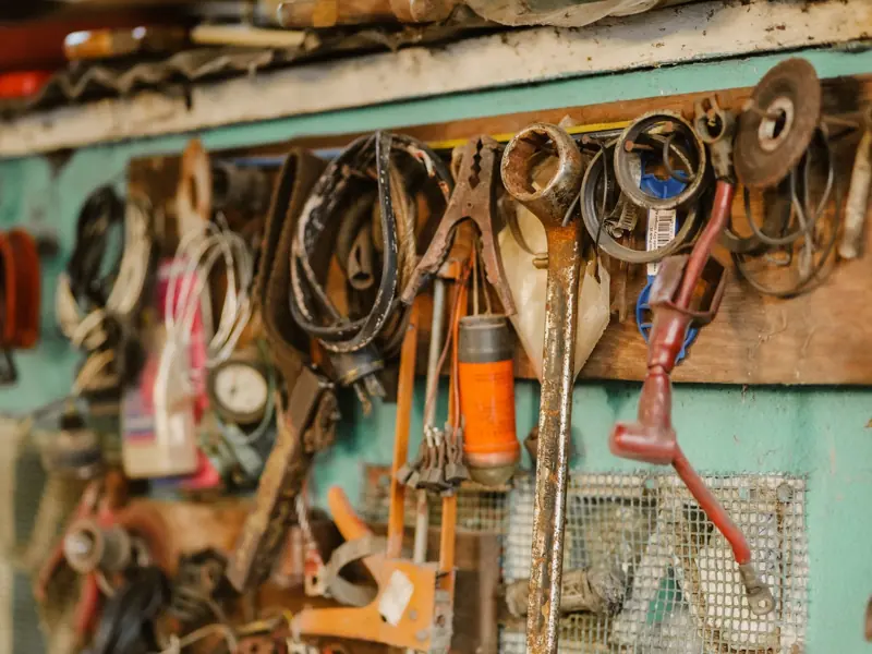 A collection of vintage tools hanging on a workshop wall, showcasing a rustic and messy appeal.