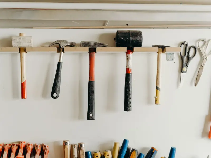 Neatly organized tools hanging on a workshop wall, including hammers and scissors.