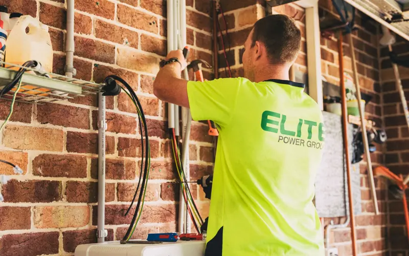 Electrician performing solar battery installation for sustainable energy storage in a home setting.