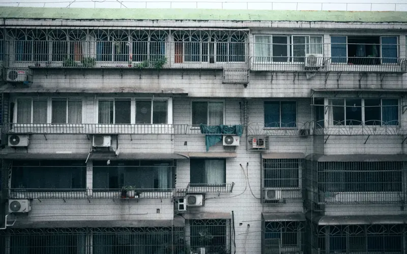 Facade of a multi-story apartment building with air conditioning units visible on each floor.