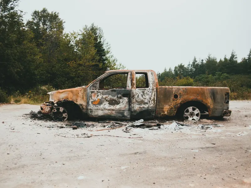 Image of a rusty, burnt-out truck in an outdoor setting. Perfect for concepts of decay and abandonment.