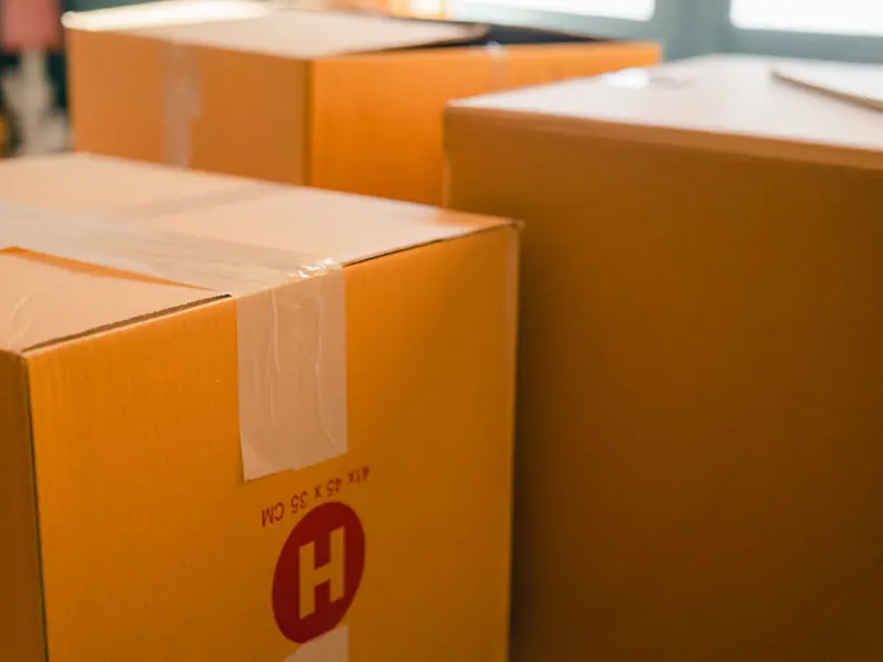 Cardboard containers sealed with sticky tape for relocation placed near window on sunny day