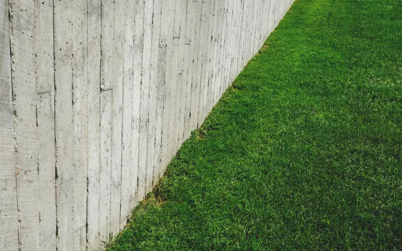 A minimalist outdoor scene featuring a wooden fence alongside a lush green lawn.