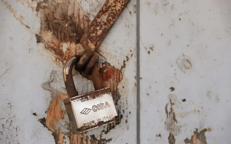 Detailed shot of a rusty padlock on a weathered door conveying security and time passage.