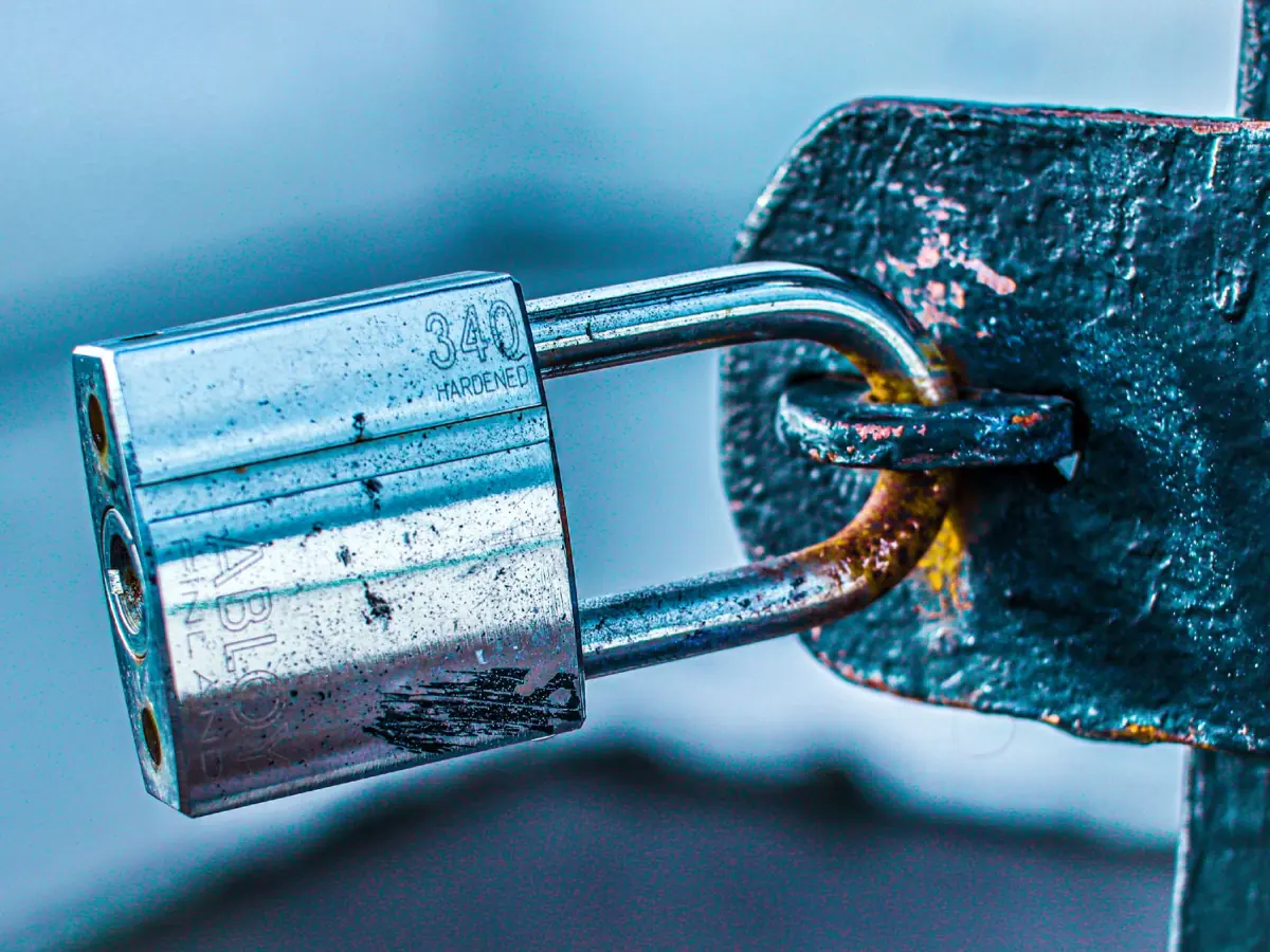 Detailed close-up of a durable padlock securing a rusted metal gate, emphasizing safety and protection.