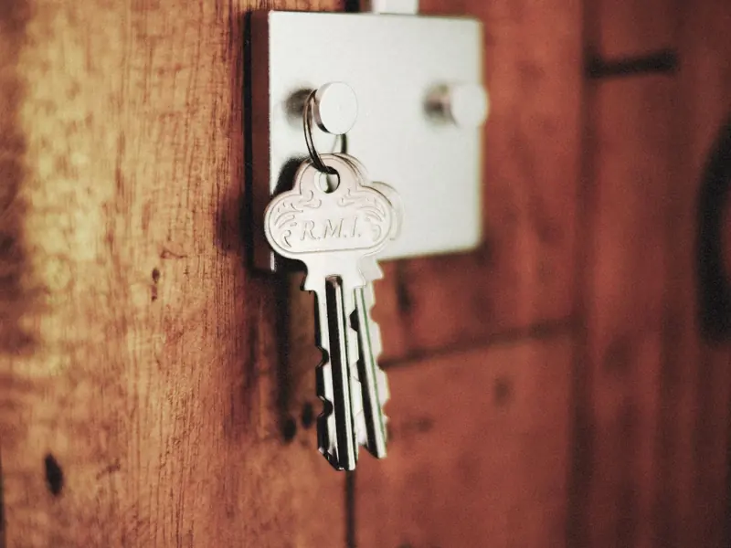 Detailed shot of keys hanging in a door lock on a wooden surface, warm tones.
