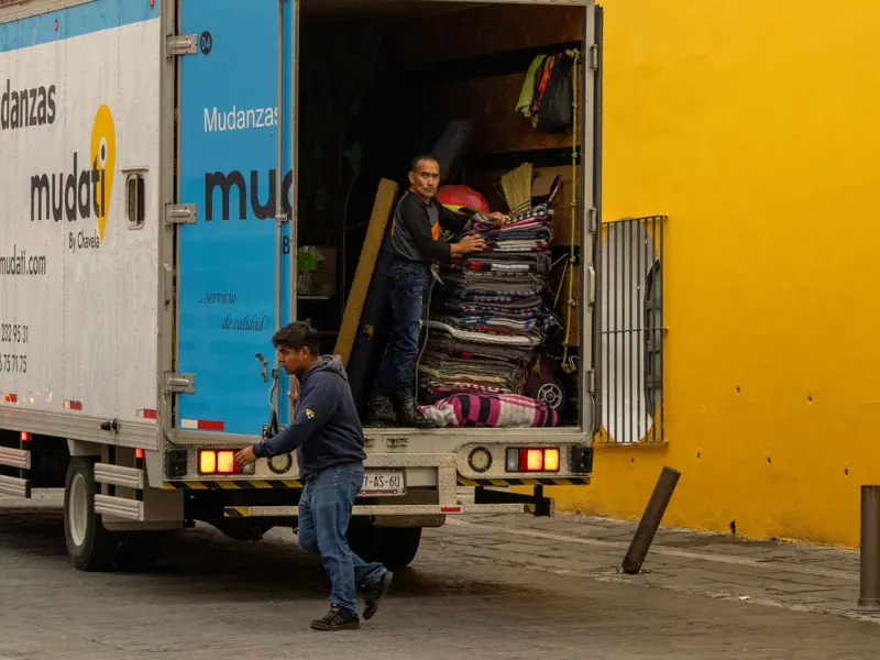 Workers loading a moving truck on a street in Mexico, urban lifestyle.