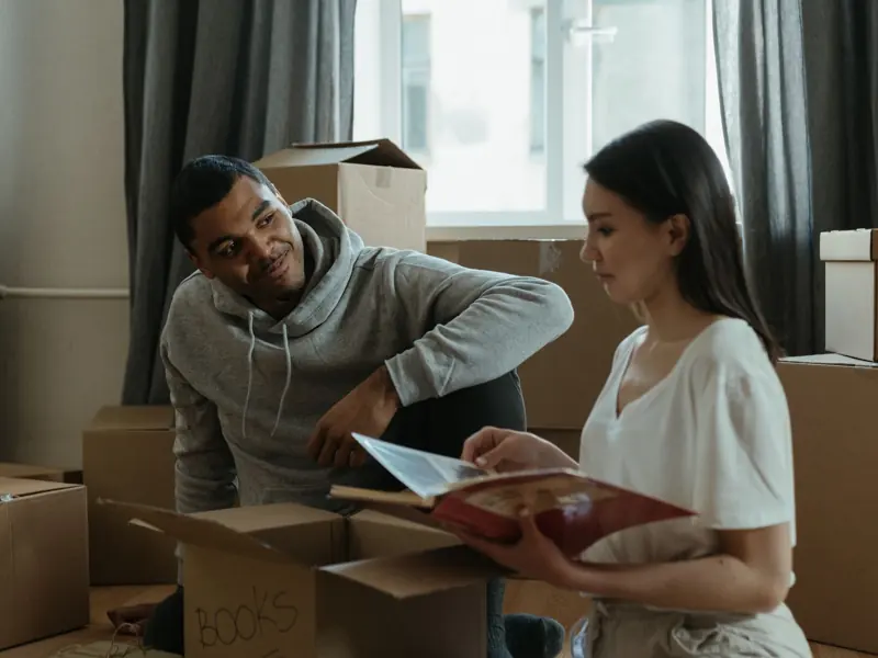 A couple exploring their new home while unpacking boxes and looking at a photo album.