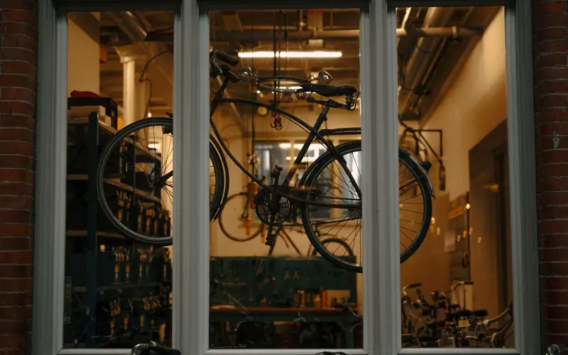 A vintage bicycle is displayed in a workshop window in Amsterdam, showcasing urban cycling culture.