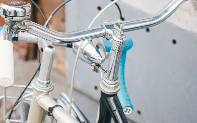 Close-up vertical shot of vintage bicycle handlebars. Outdoor urban setting capturing a classic appeal.