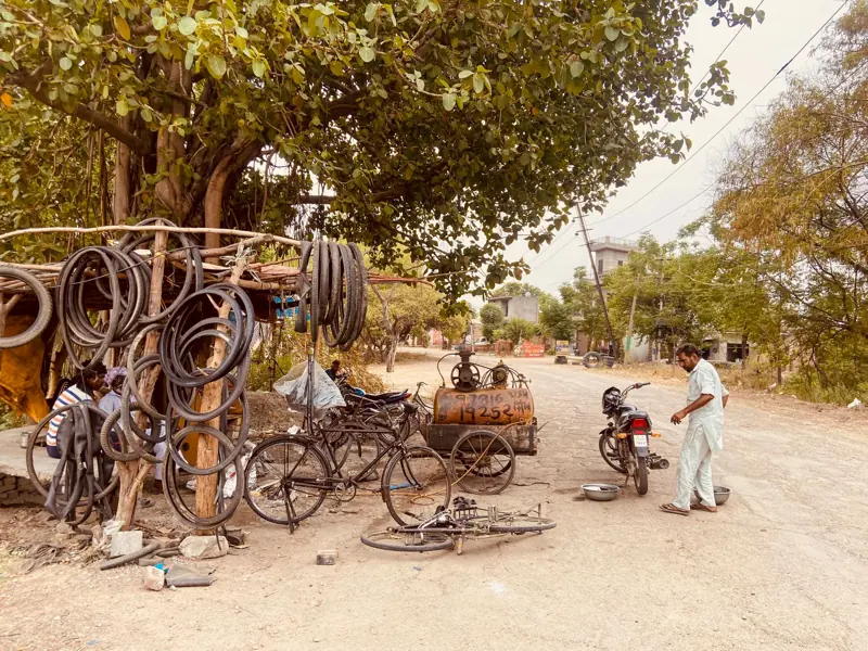 A man repairing bicycles at a makeshift repair shop under a tree in Neelon Khurd, India.
