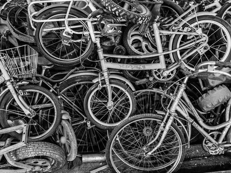 Chaotic pile of old bicycles in black and white, showcasing urban decay and recycling themes.