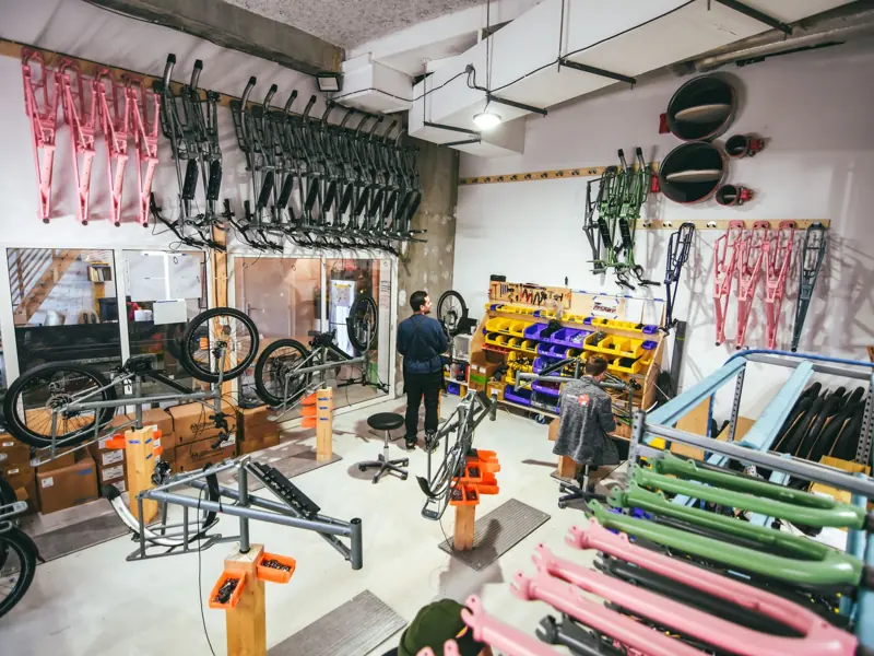 Busy bicycle workshop in Bordeaux, featuring colorful frames and various tools, with two adults working.