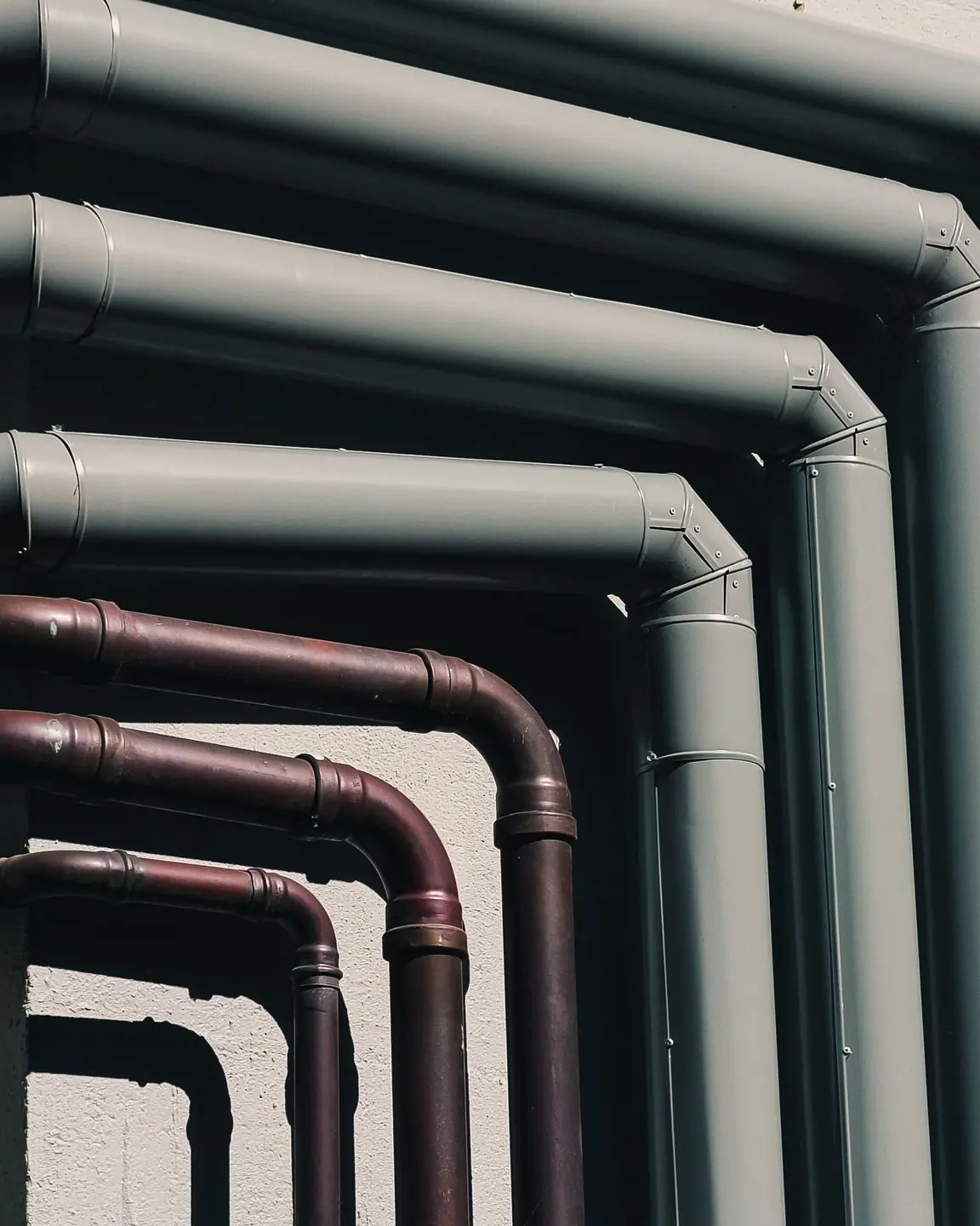 Close-up of industrial pipes forming a pattern on a building's exterior wall, shot outdoors.