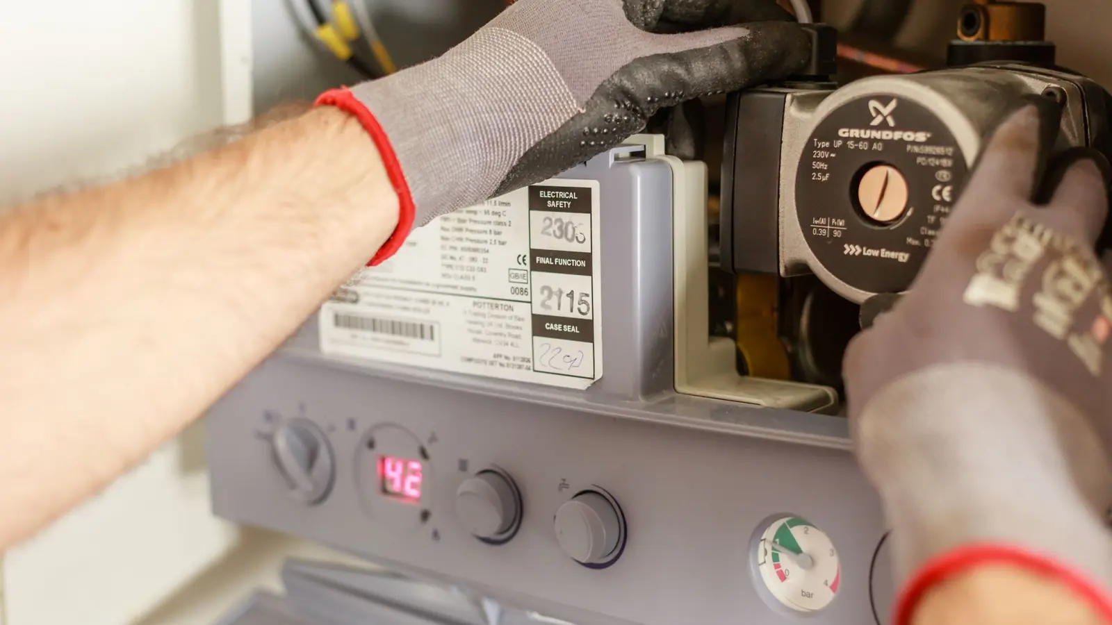 Close-up of hands adjusting a boiler system with precise instrumentation, showing maintenance work.