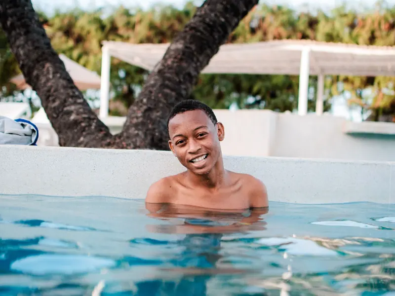 A happy man enjoying a relaxing swim in an outdoor pool during summer.