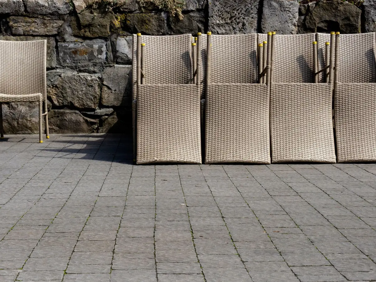 Wicker outdoor chairs arranged against a rustic stone wall in Lviv, Ukraine.