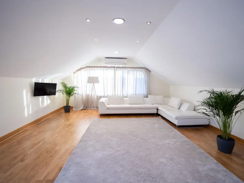 Spacious attic living room with white sofa, hardwood floor, and modern decor.