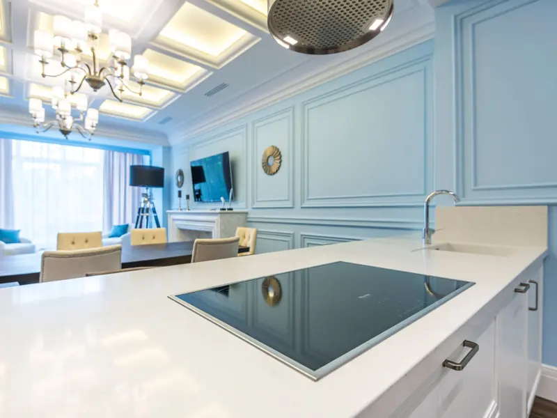 Stylish modern kitchen interior with elegant blue accents, including a countertop and chandelier lighting.