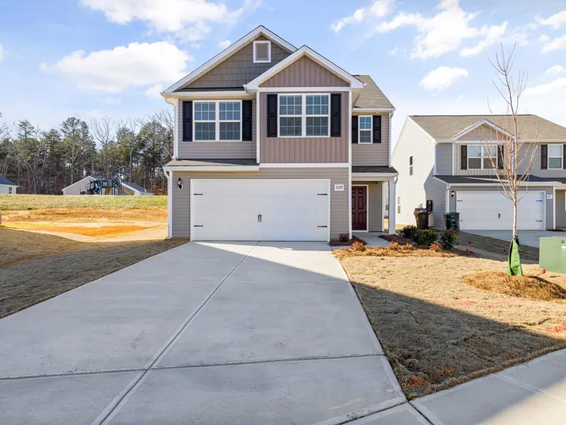 Contemporary suburban house with a wide driveway and landscaped front yard.
