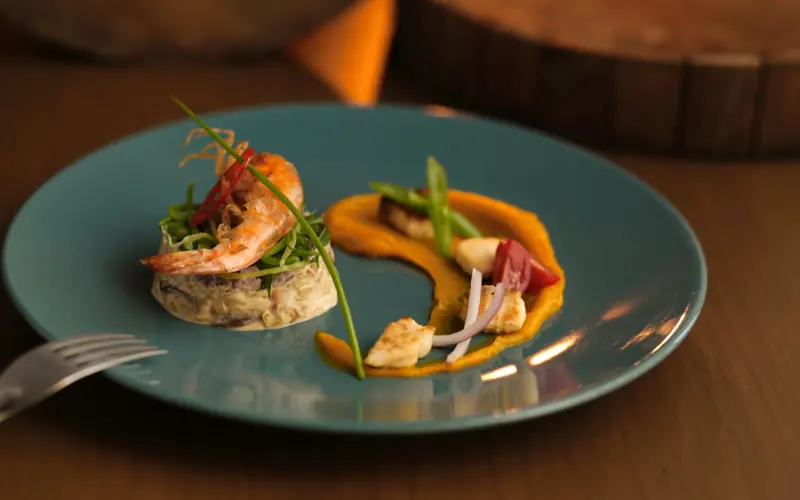 A gourmet shrimp appetizer elegantly plated with colorful vegetables and sauce.