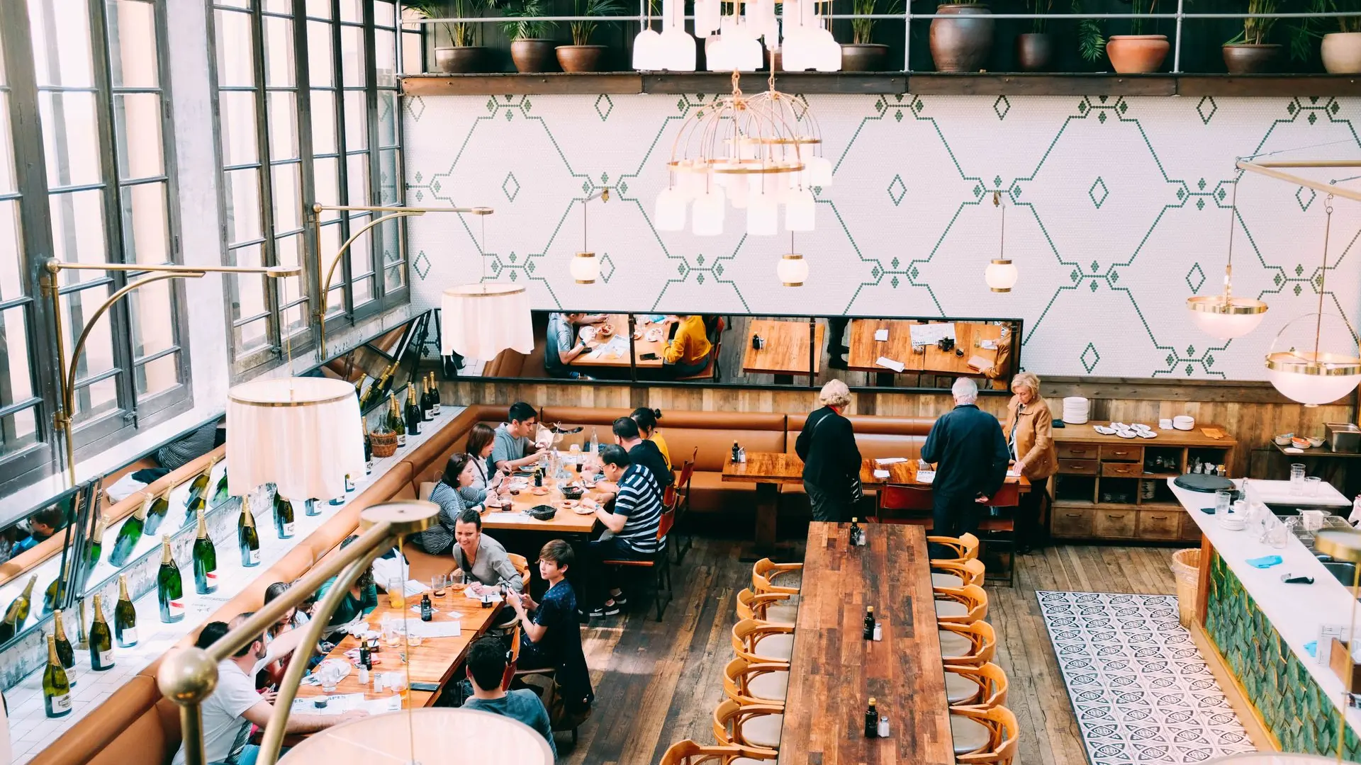 Spacious restaurant with stylish interior design, featuring wooden tables and a group of diners enjoying a meal.