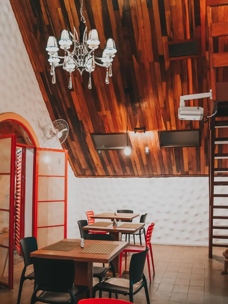 Warm and inviting dining area featuring a wooden ceiling, elegant chandelier, and modern furniture.