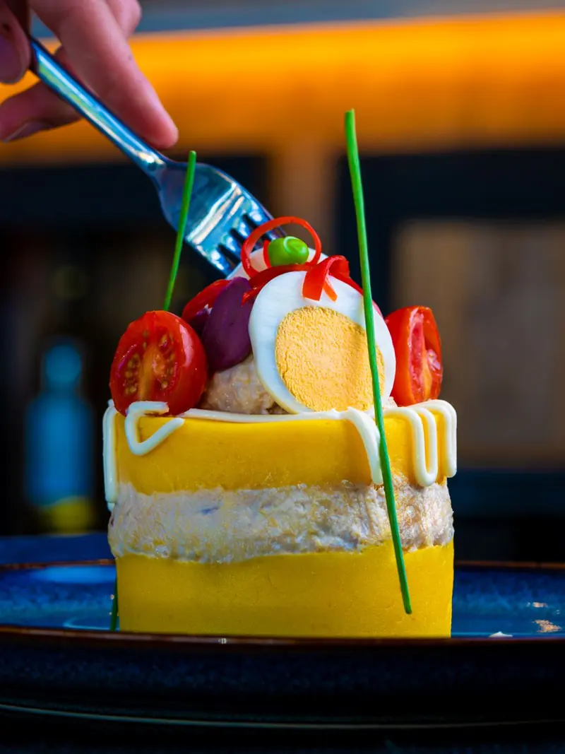 Close-up of a gourmet dish with eggs, tomatoes, and garnish, captured indoors.