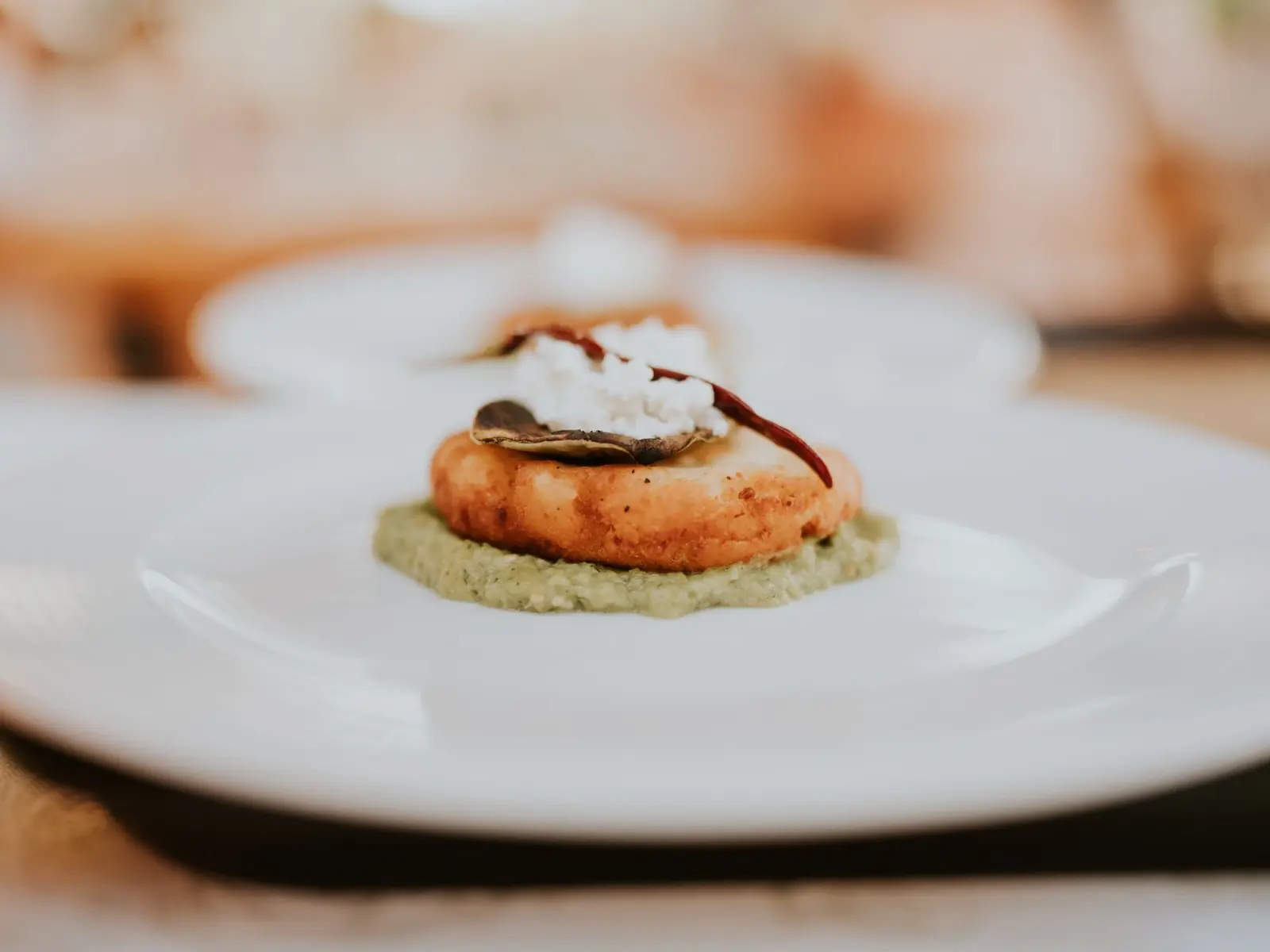 A gourmet dish elegantly plated with an appetizer served on a white plate in a restaurant setting.
